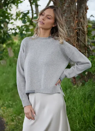 Woman wearing a porridge and grey crew neck sweater by Fisherman Out of Ireland, made from wool-cashmere blend with contrast blanket stitch detail.